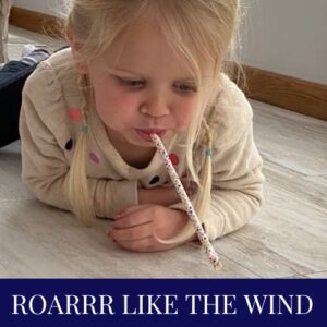 Child using a straw to blow an object.